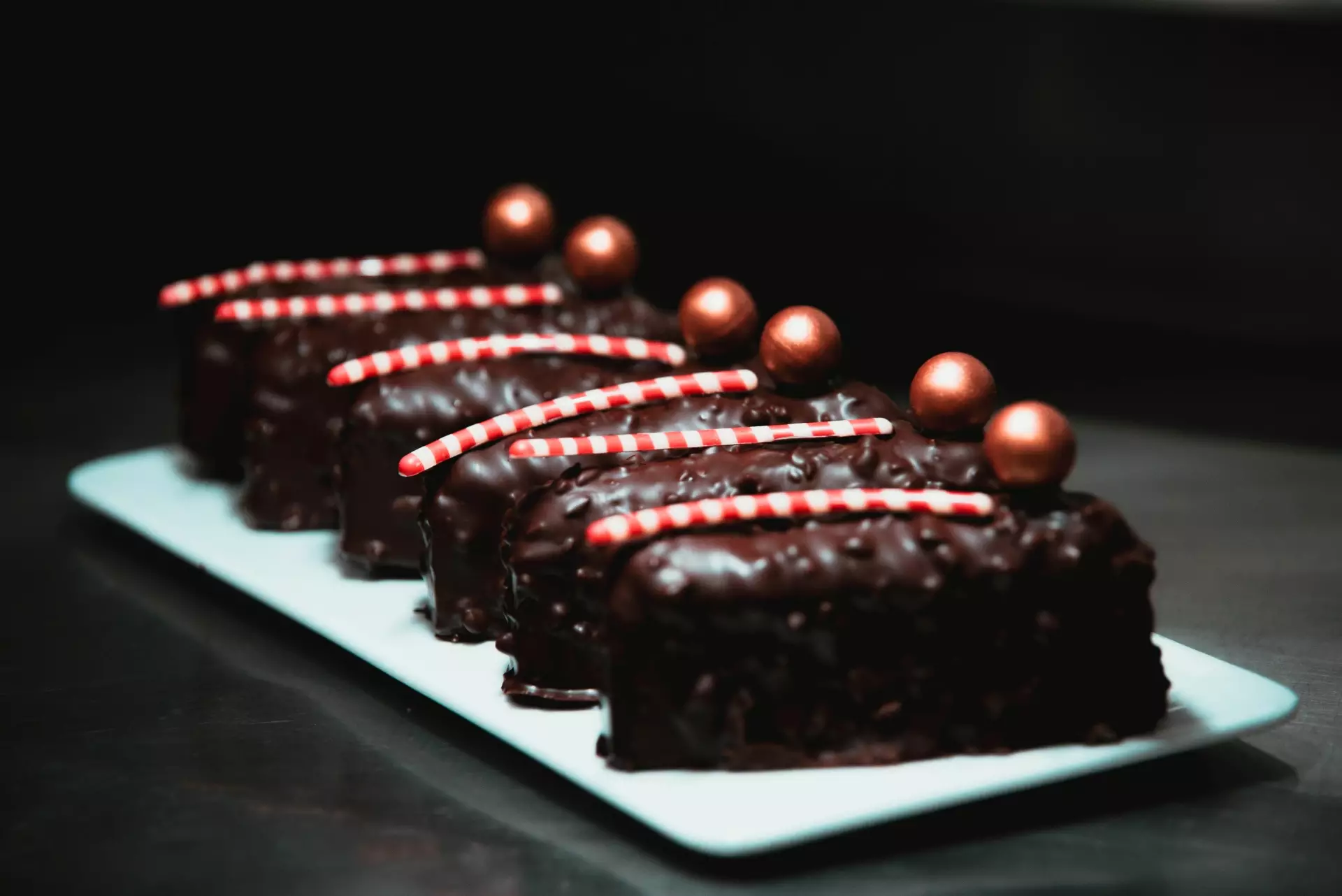 Triángulos de chocolate decorados con un bastón rallado blanco y rojo y una bola dorada