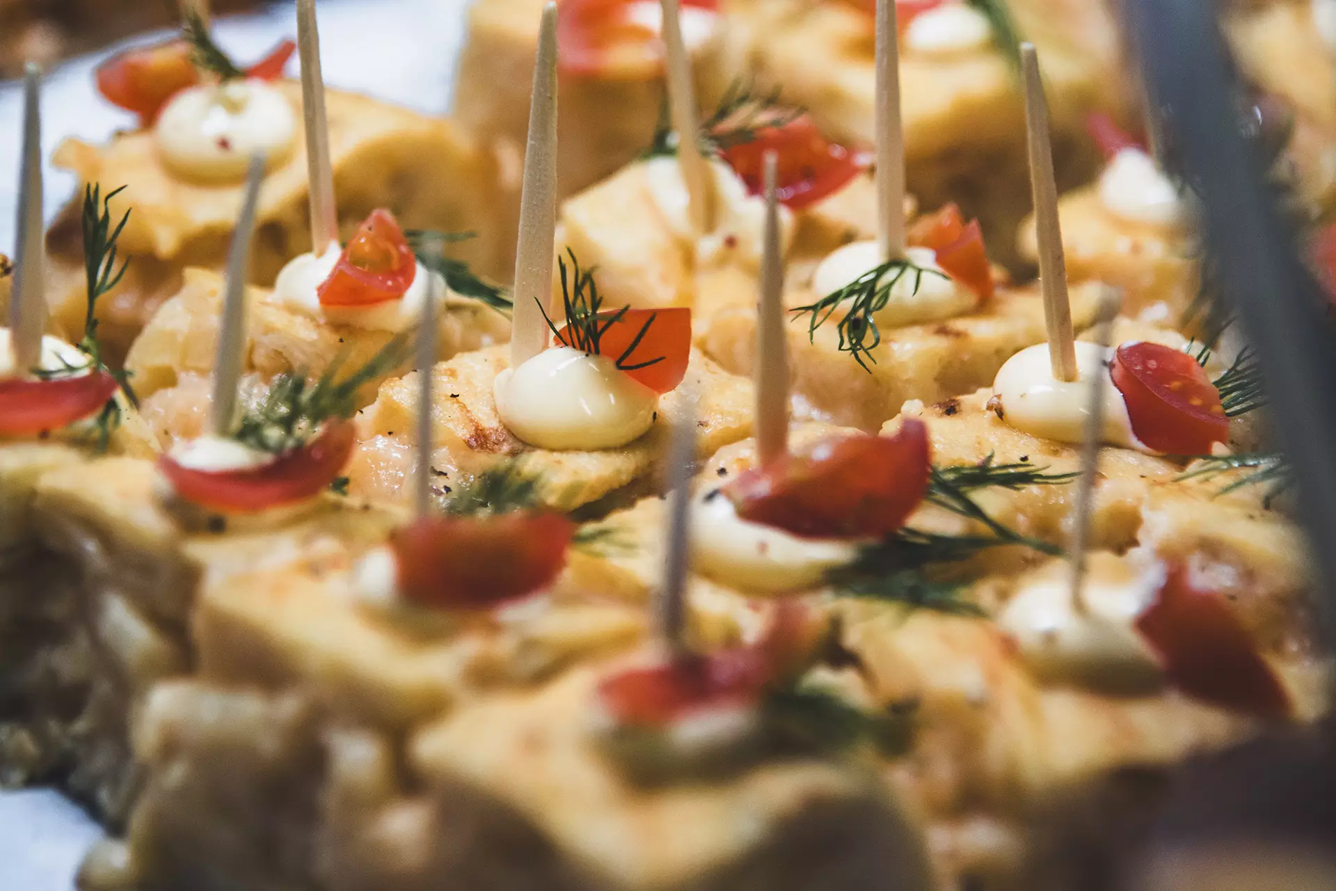 Tortilla de patata cortada en cuadrados con tomate cherry y mayonesa
